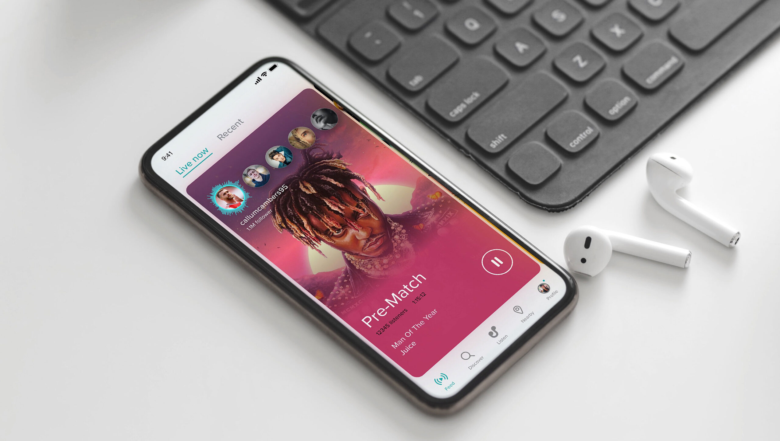 Iphone showing an open music app lays near a keyboard and headphones on a desk