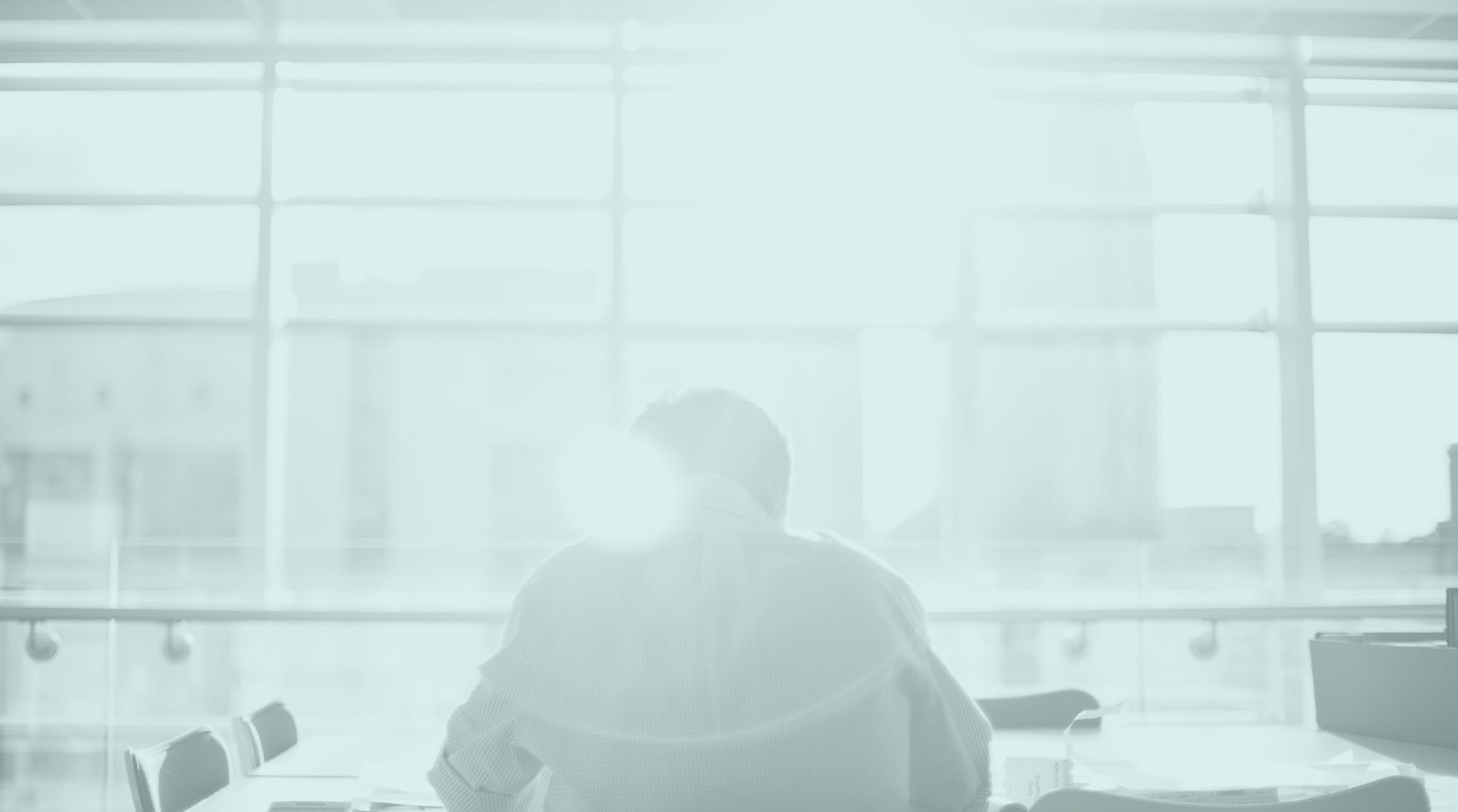 Men sitting in an office with his back towards a viewer. The context is that the project is about improving mental health among workers