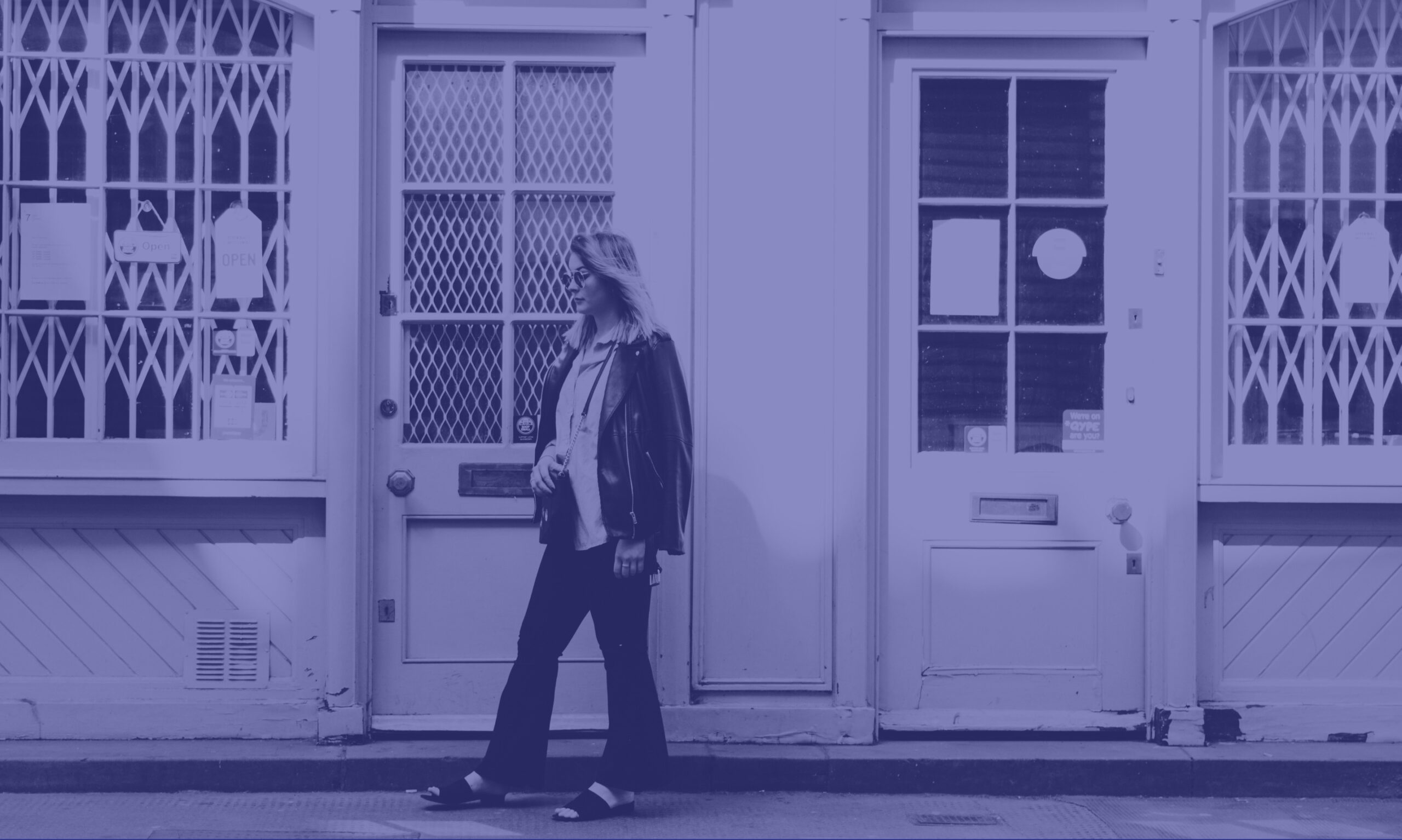 A photo with a purple overlay showing a woman in sunglasses walking down the high street